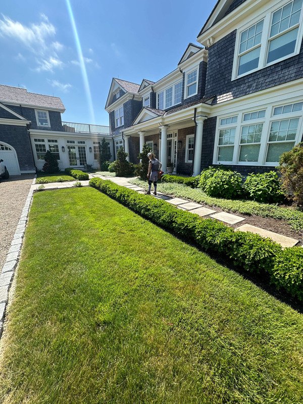 Front yard landscape design with stone walkway and manicured lawn at Cape Cod home in Yarmouth Port by KB Landscape Construction